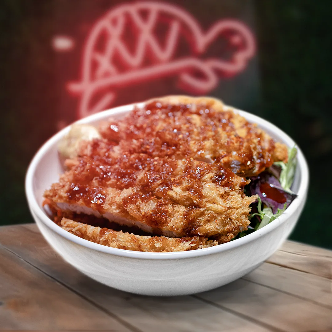 A crispy chicken bowl under a pink turtle neon sign