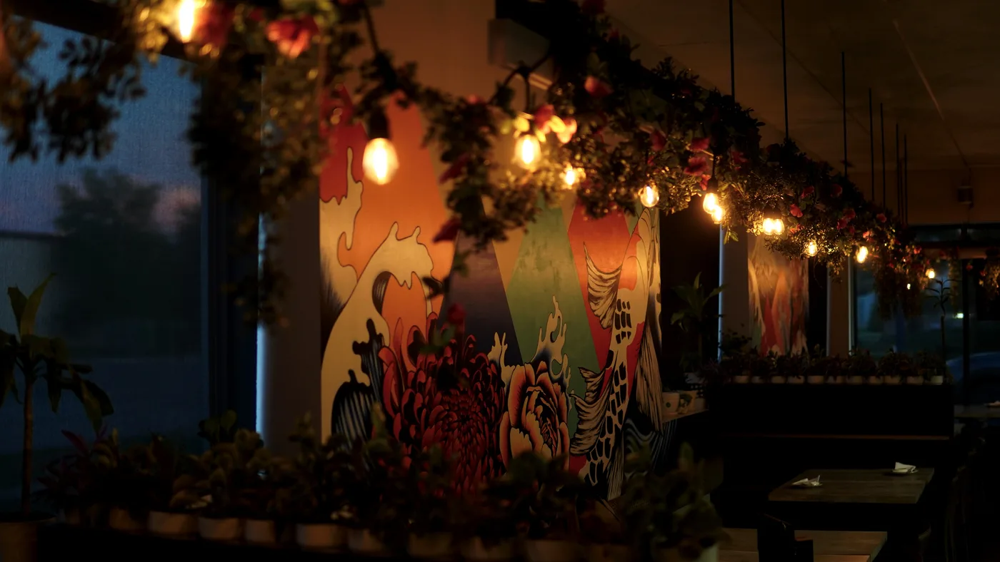 String lights and hanging plants along a painted wave-and-dragon mural